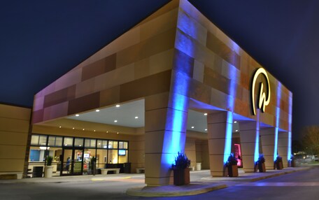 A hotel with a modern design, featuring a prominent illuminated logo on the facade.