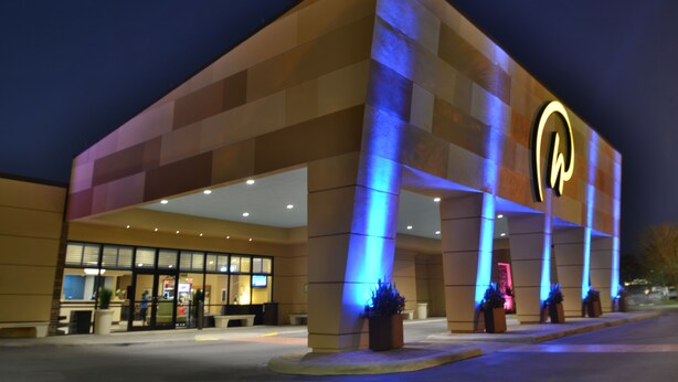 A hotel with a modern design, featuring a prominent illuminated logo on the facade.