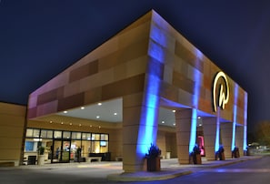 A hotel with a modern design, featuring a prominent illuminated logo on the facade.