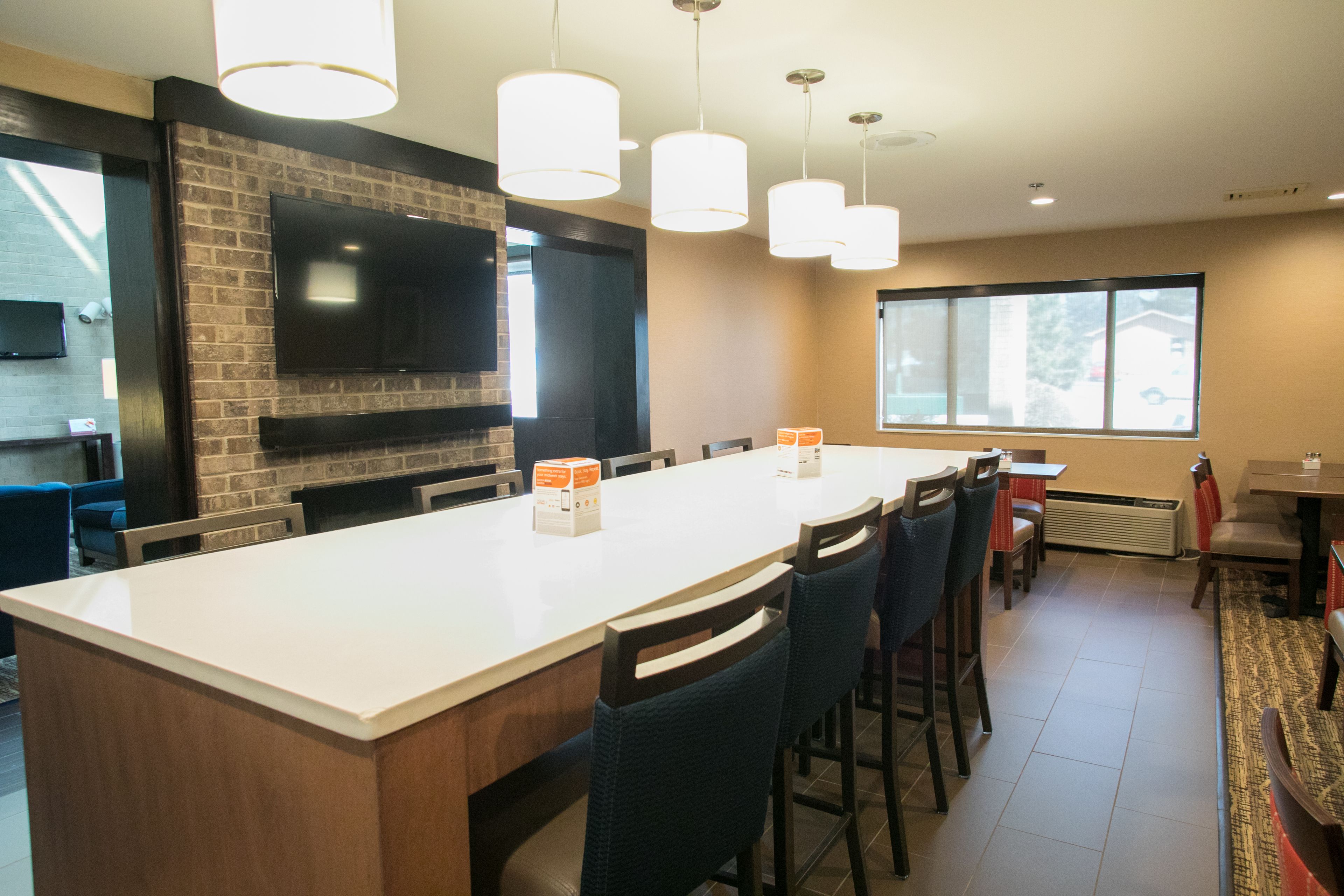 A modern kitchen with a large island, built-in TV, and pendant lighting.