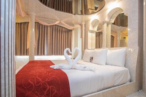 A hotel room with a large bed, a red patterned bedspread, and two swan-shaped towels. - Comfort Suites Oakbrook Terrace - Chicago West (Villa Park)