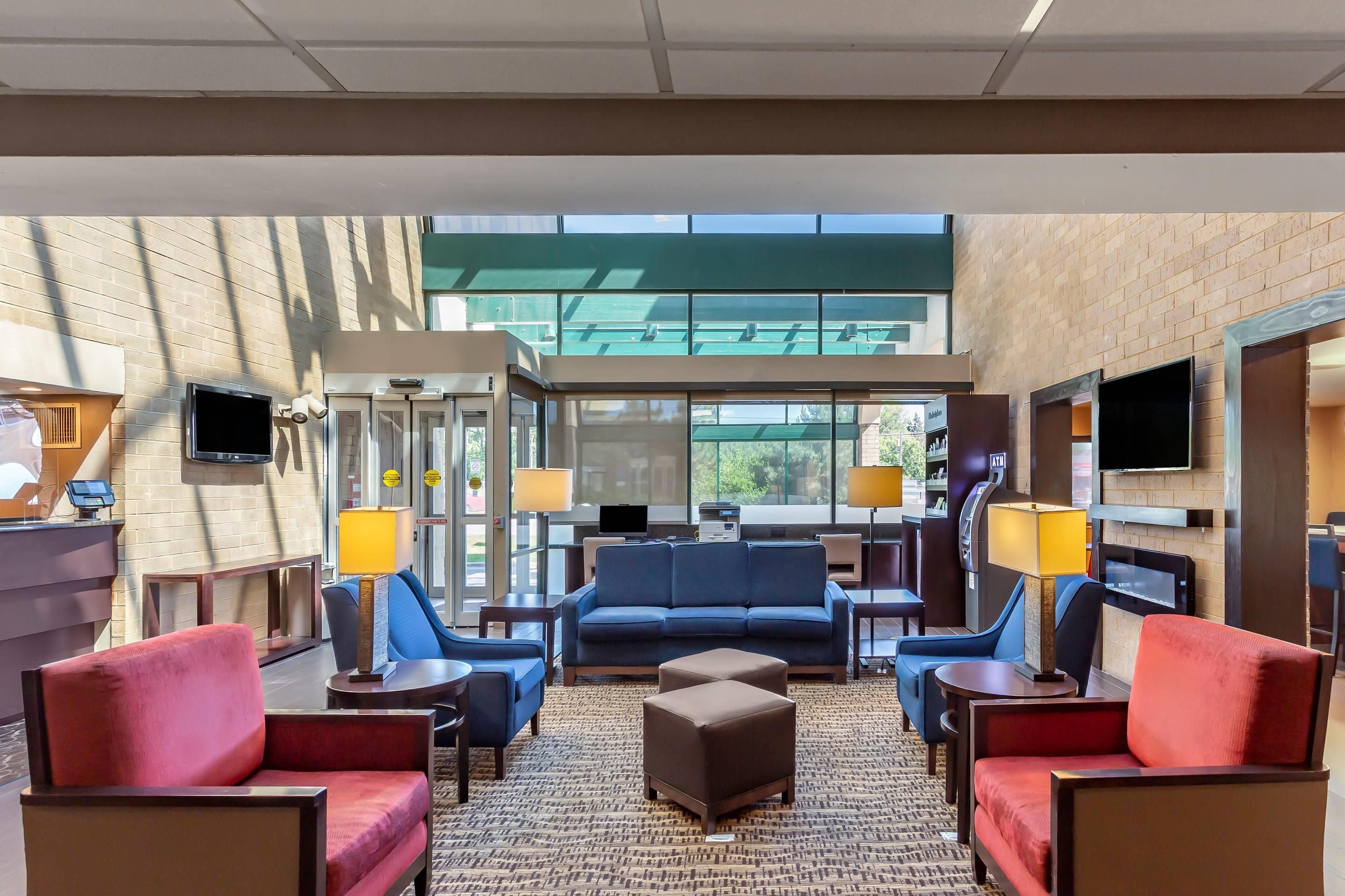 A hotel lobby with a seating area, a reception desk, and a large window.