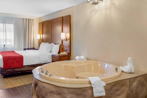 A hotel room with a large bed, a bedside table with a lamp, a bathroom with a bathtub, and a shower area. - Comfort Suites Oakbrook Terrace - Chicago West (Villa Park)