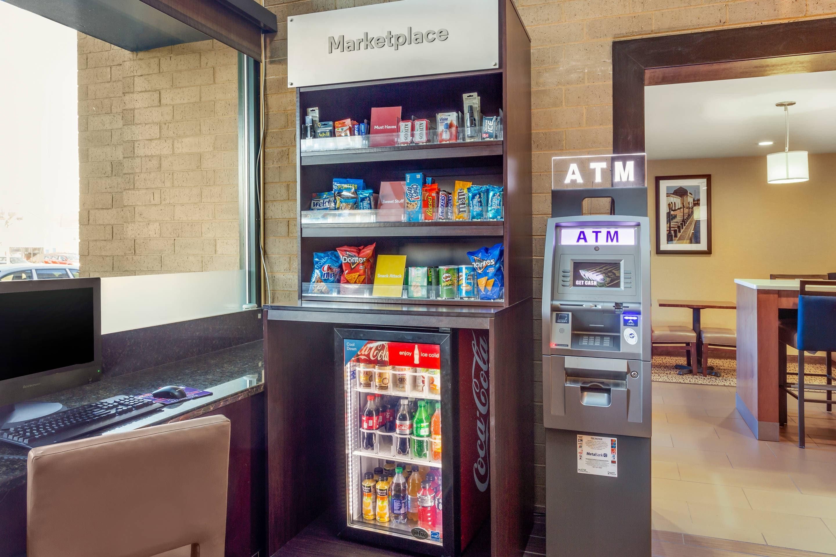 A vending machine with snacks and a Coca-Cola refrigerator, an ATM, and a sign for a marketplace.