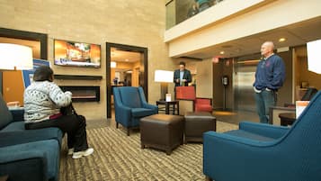 A lobby with seating, a TV screen, and a fireplace.