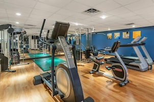 Un gimnasio con equipo de ejercicio, un espejo y una pared azul con imágenes.