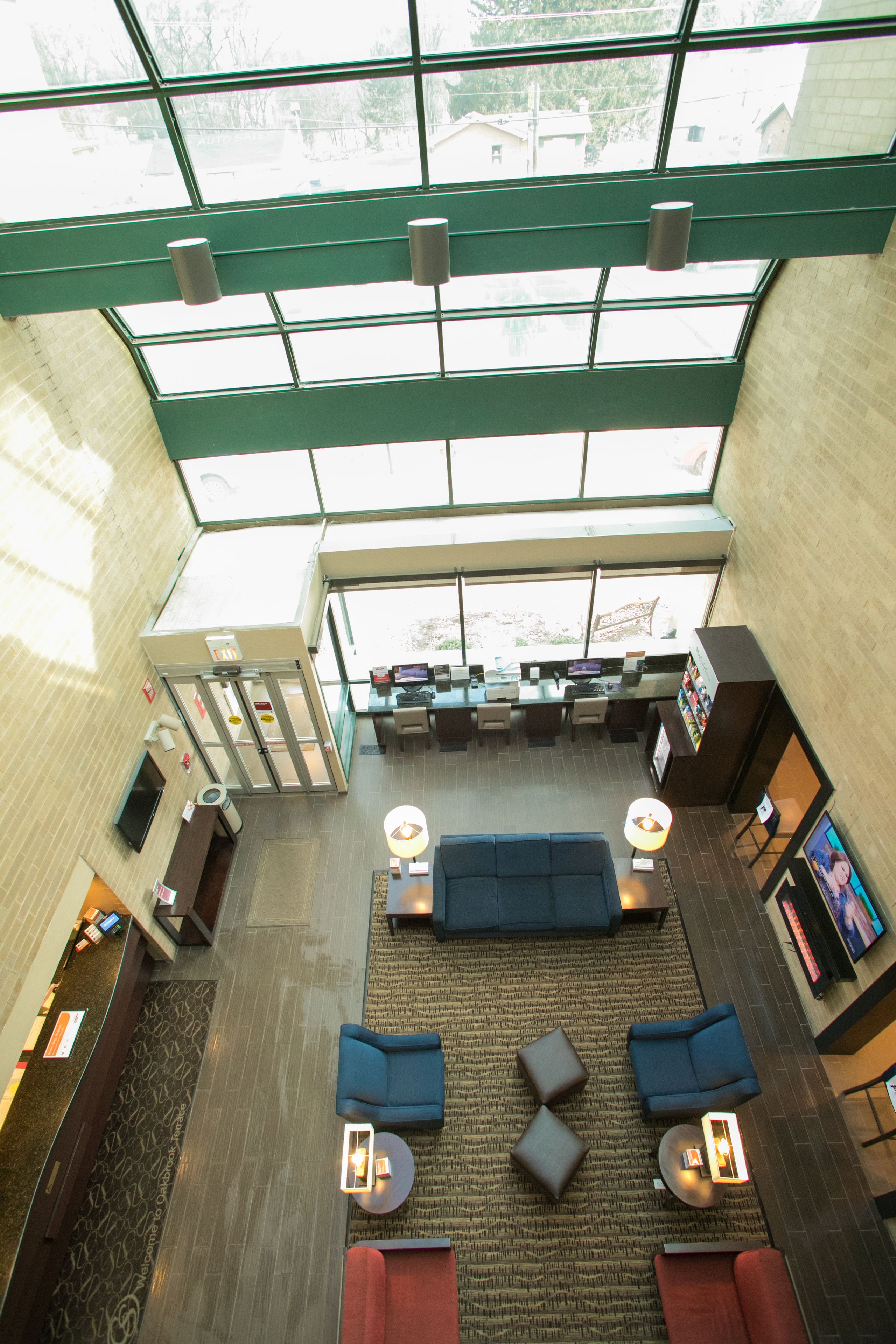 A spacious lobby with a high ceiling, large windows, and a seating area with sofas and tables.