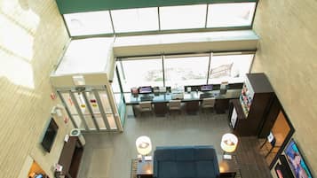 A spacious lobby with a high ceiling, large windows, and a seating area with sofas and tables.