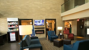 A hotel lobby with seating areas, a television, a fireplace, and a vending machine. - Comfort Suites Oakbrook Terrace - Chicago West (Villa Park)