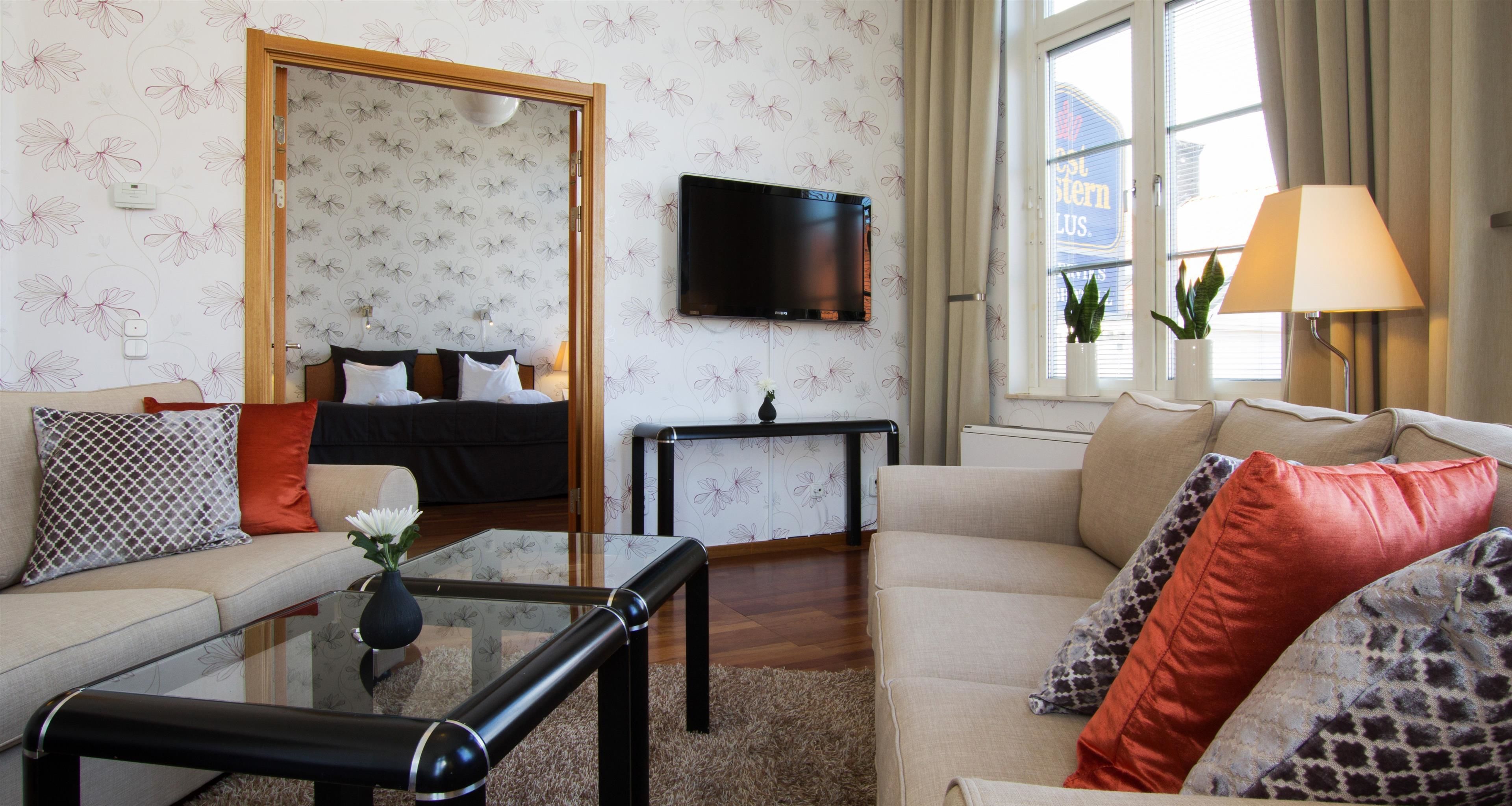 A modern living room with a sofa, coffee table, and a TV mounted on the wall.
