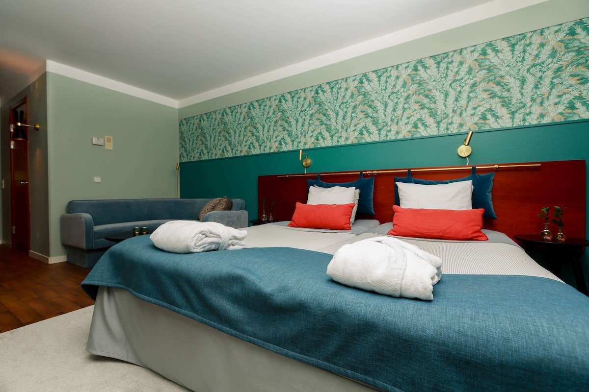 A hotel room with a large bed, a sofa, and a small table.