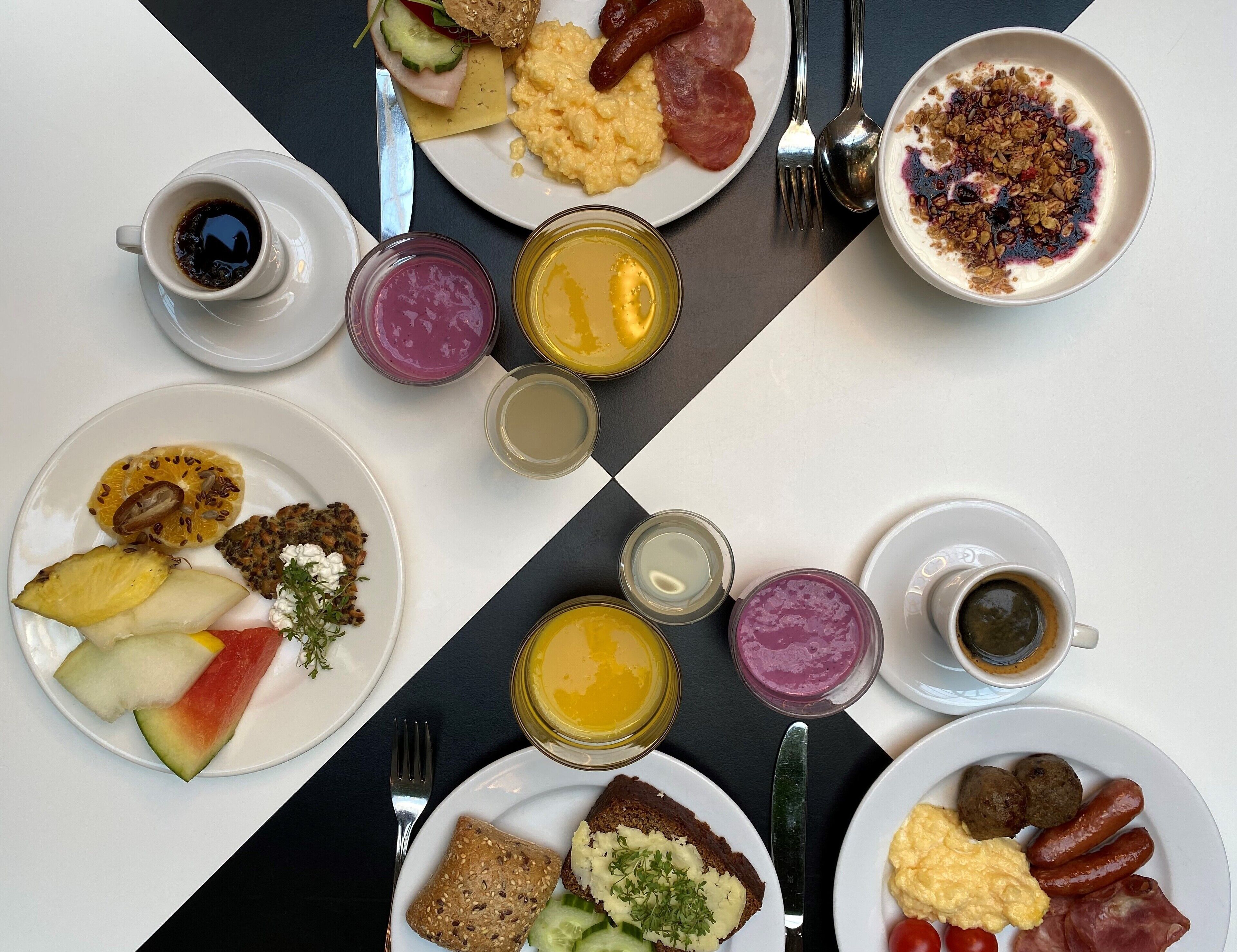 A breakfast setting with various dishes, including scrambled eggs, sausages, and toast, along with cups of coffee and juice.