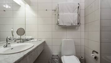 A bathroom with a sink, mirror, towel rack, toilet, and toilet paper.