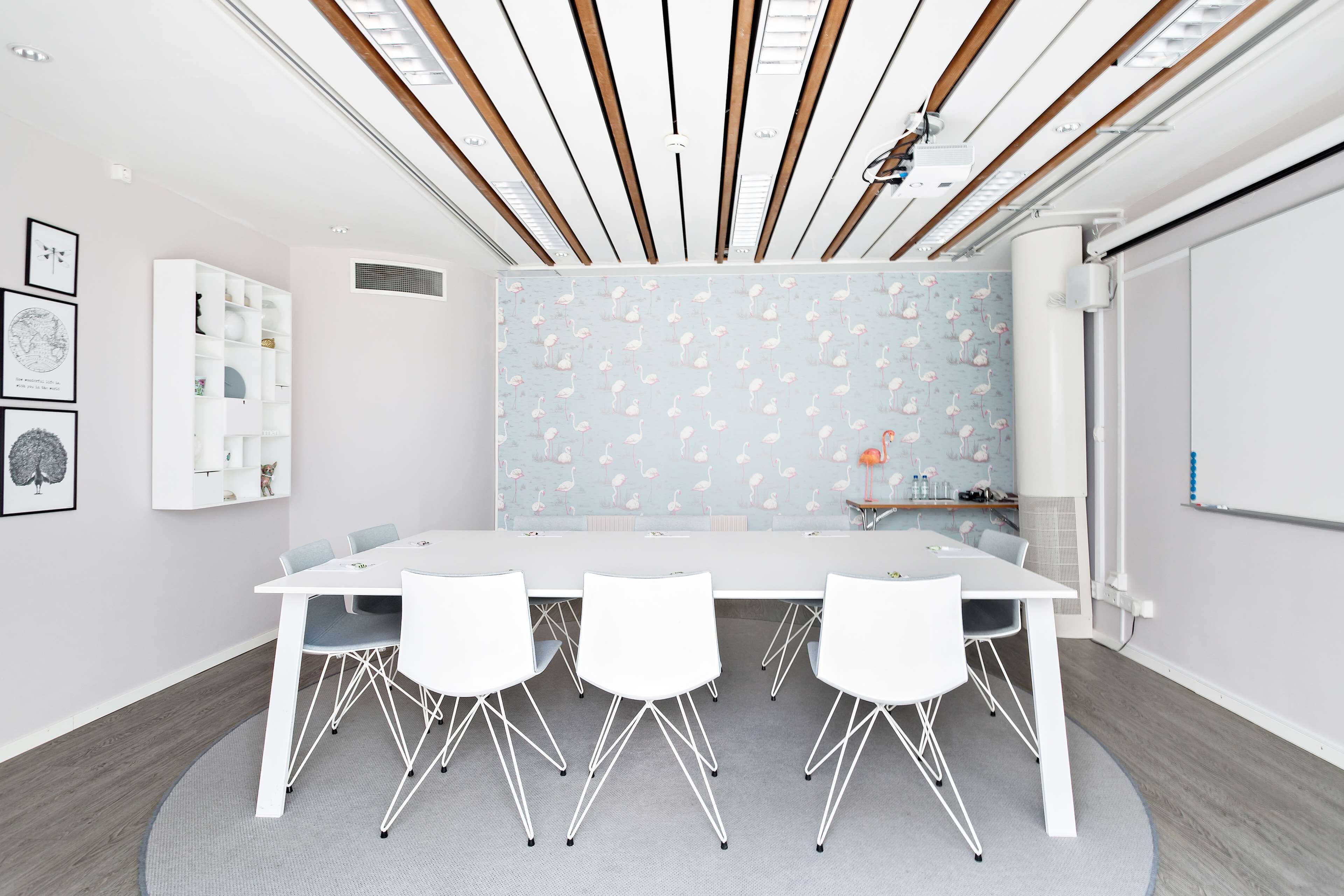 A conference room with a white table, four chairs, a whiteboard, and a patterned wall.