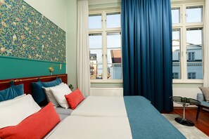 A hotel room with a large bed, a small table, and a view of buildings through the window. - Best Western Plus Vasterviks Stadshotell (Vastervik)