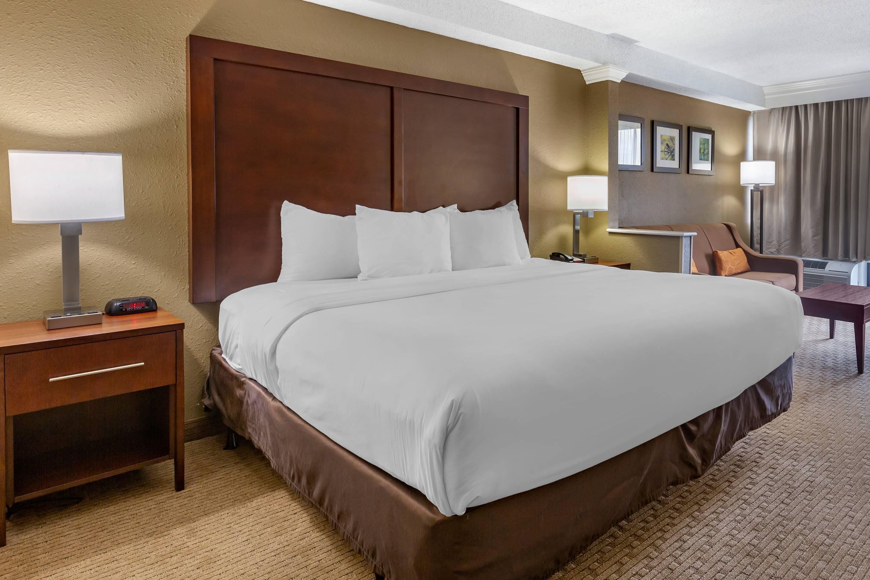 Une chambre d’hôtel avec un grand lit, des tables de chevet, un bureau et une chaise.