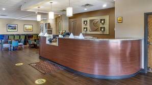 A hotel reception area with a curved counter, seating area, and framed artwork on the walls.
