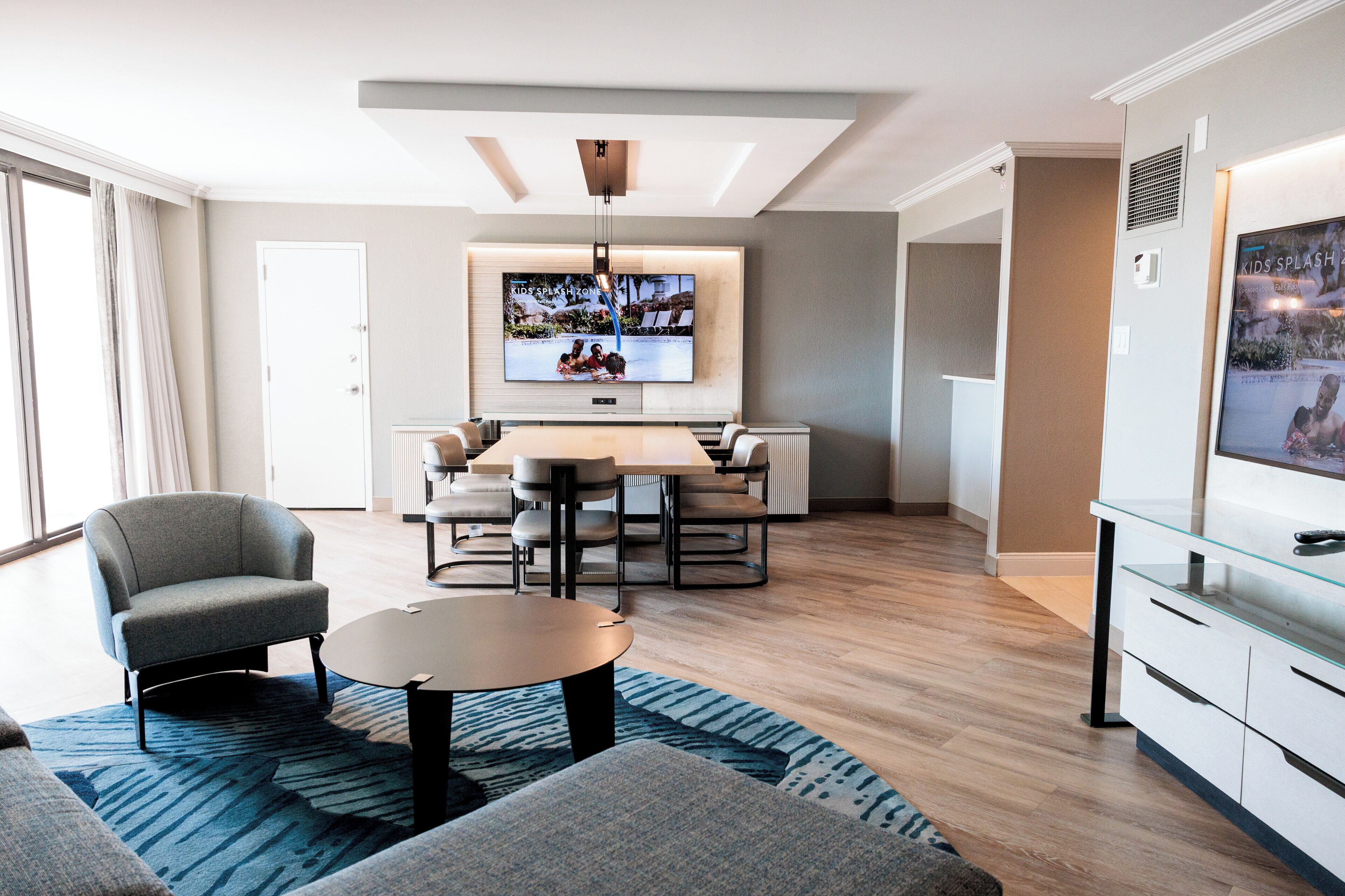 A modern living room with a sofa, coffee table, and a dining area with chairs and a table.