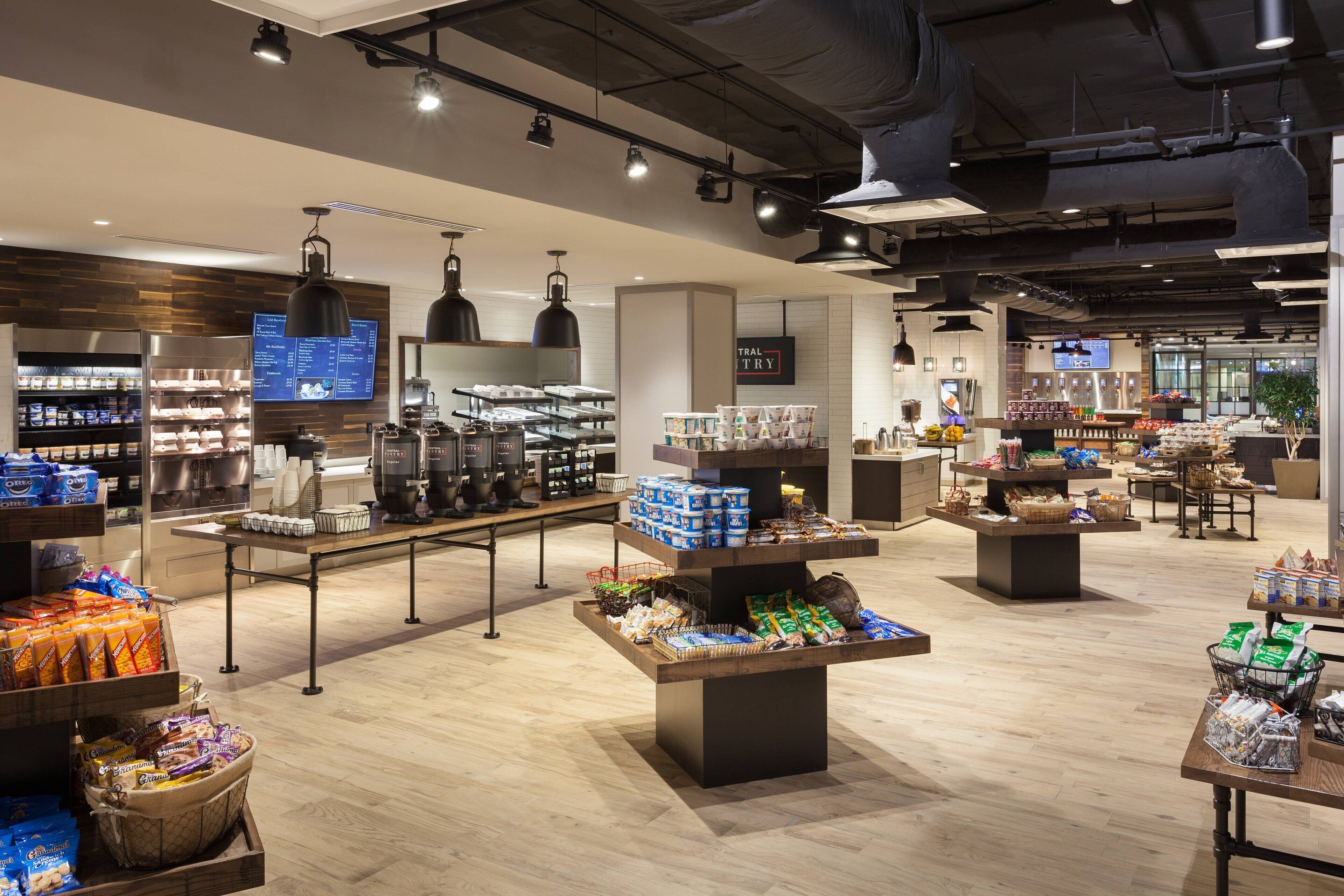 A spacious, well-lit store with various food items and beverages on display, including a coffee station and shelves stocked with snacks.