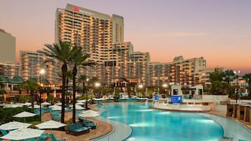 A Marriott hotel with a large pool area, multiple lounge chairs, and umbrellas.