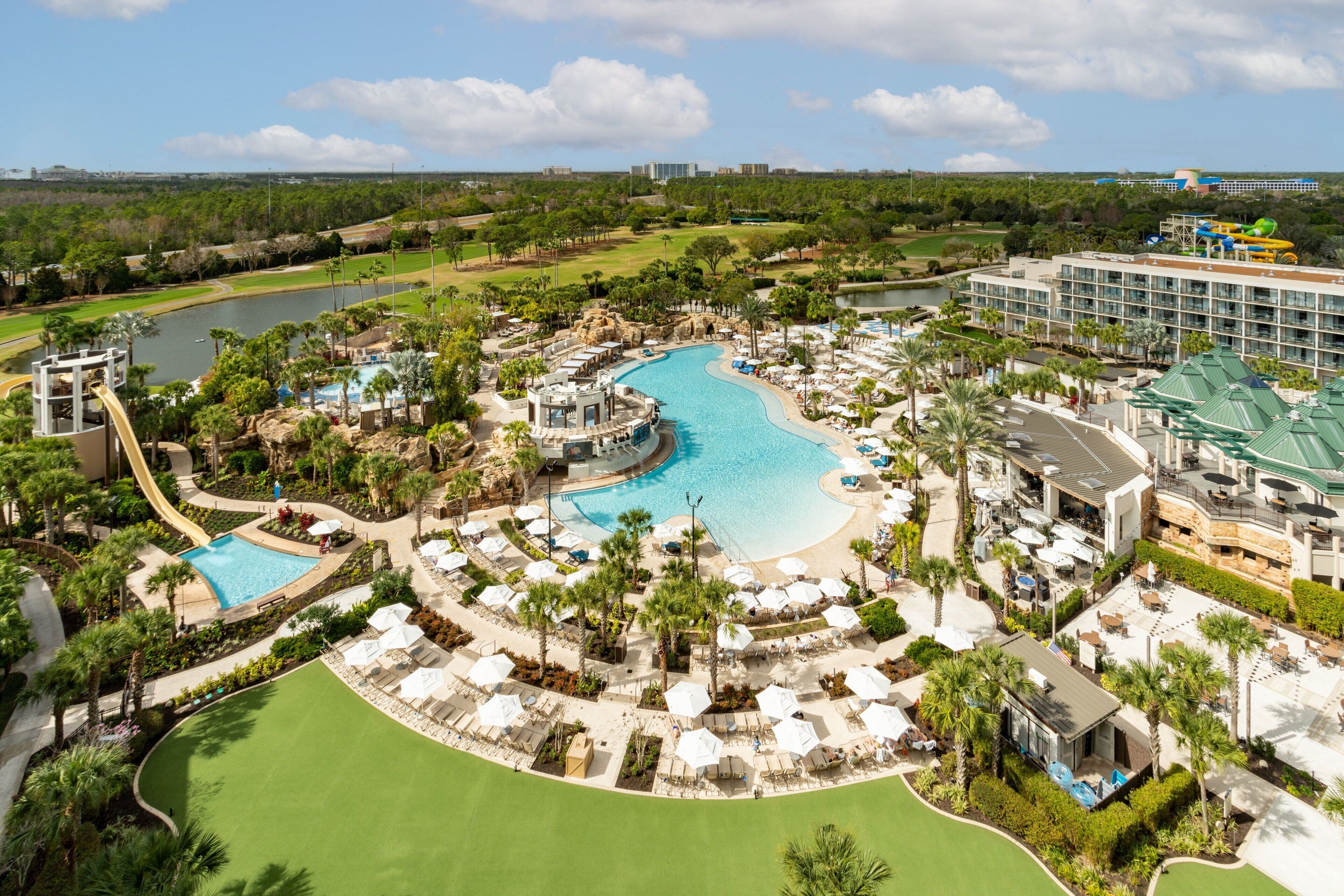 A resort with a large central pool, multiple smaller pools, a golf course, and a water park.