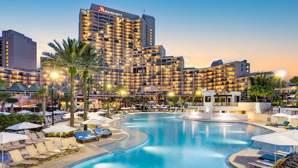 Un hôtel Marriott doté d’une grande piscine, de chaises longues et de palmiers.