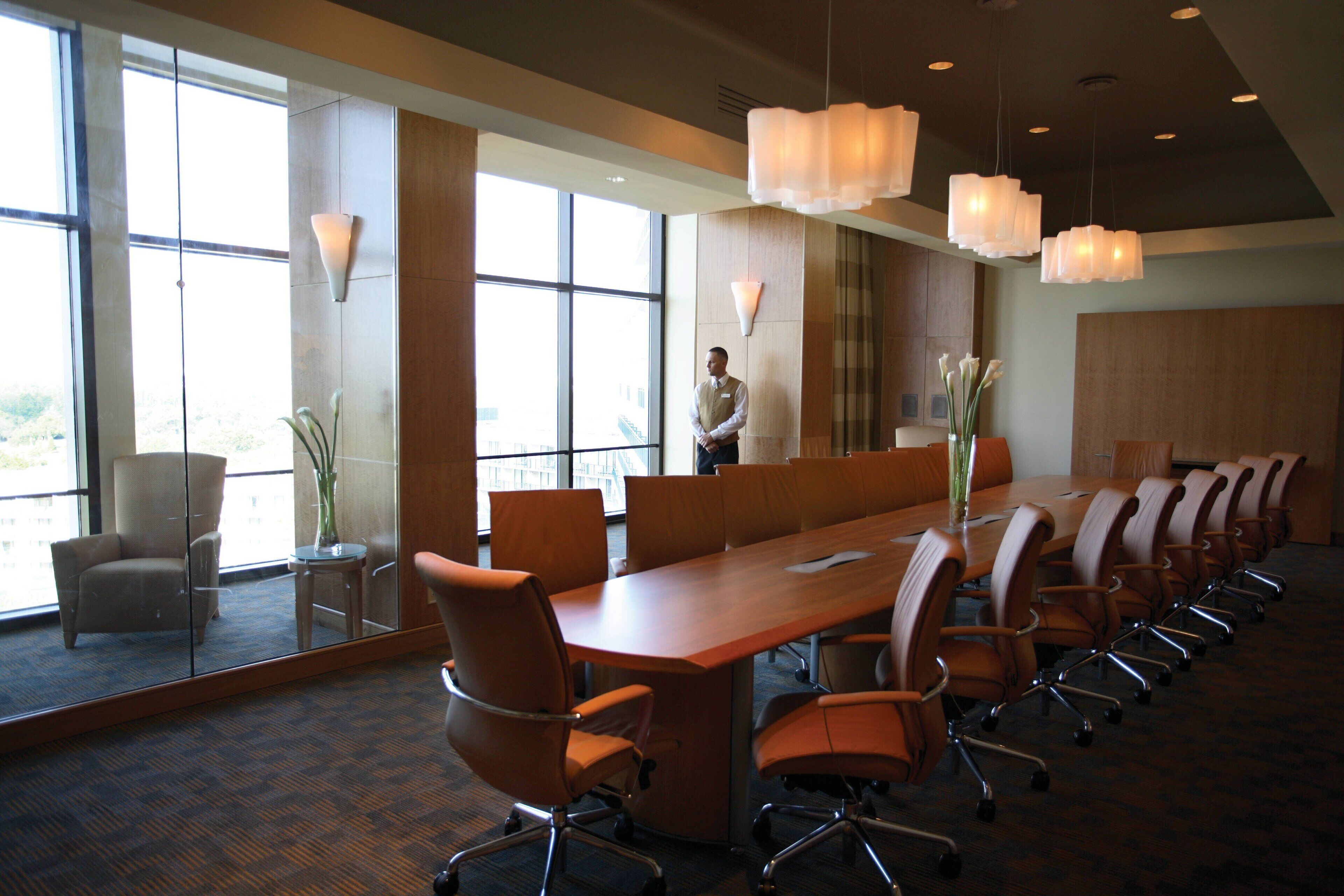 A conference room with a long table, chairs, and large windows.