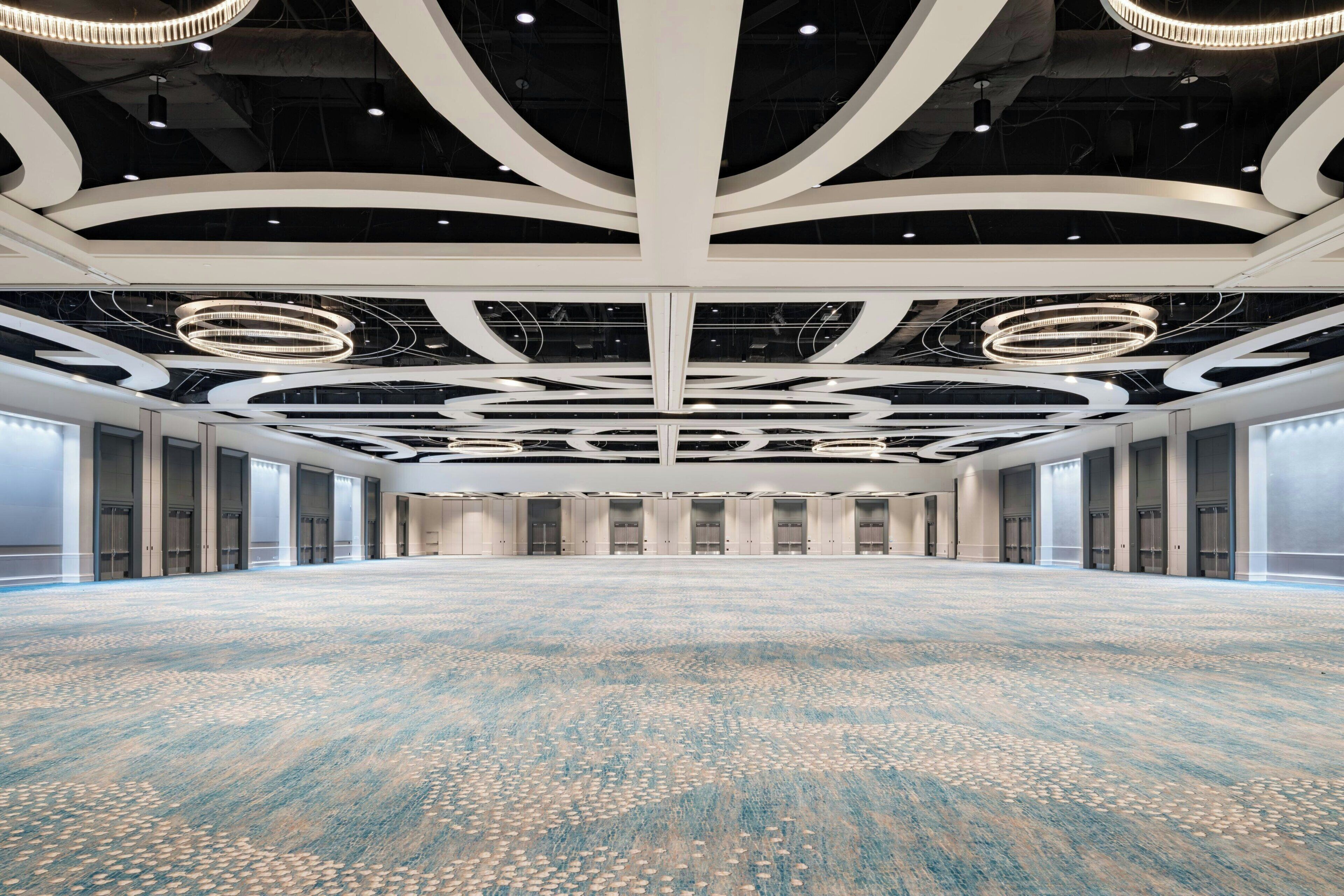 A spacious conference room with a patterned carpet, modern ceiling design, and large windows.