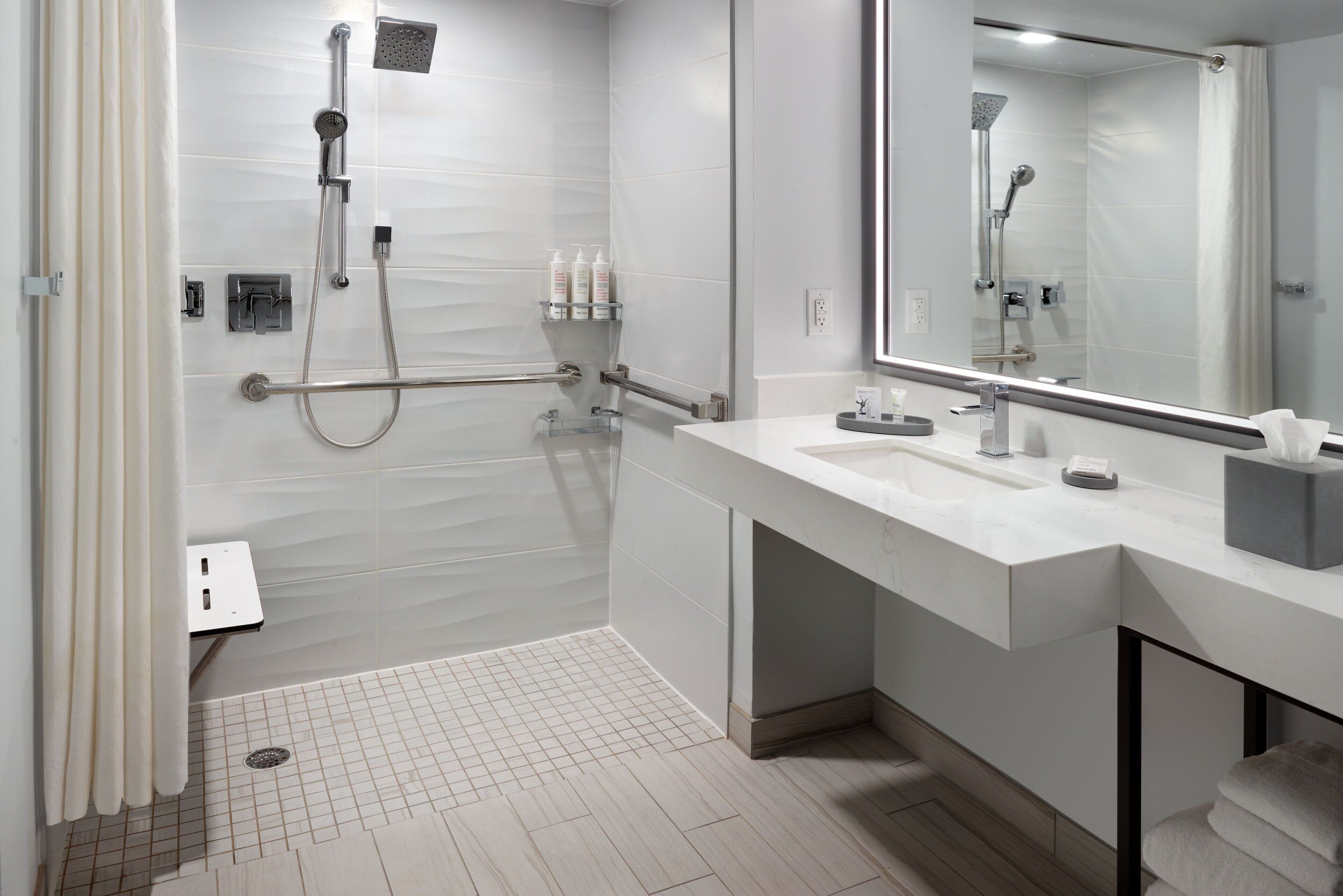 Un bagno moderno con doccia a filo pavimento, lavabo con specchio e porta asciugamani.