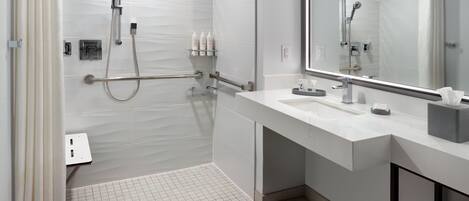 Un bagno moderno con doccia a filo pavimento, lavabo con specchio e porta asciugamani.