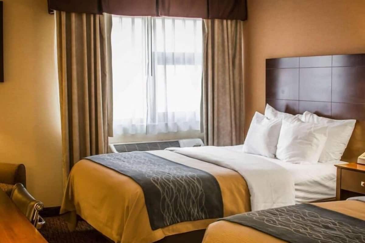 A hotel room with a bed, bedside tables, a desk, and a window with curtains.