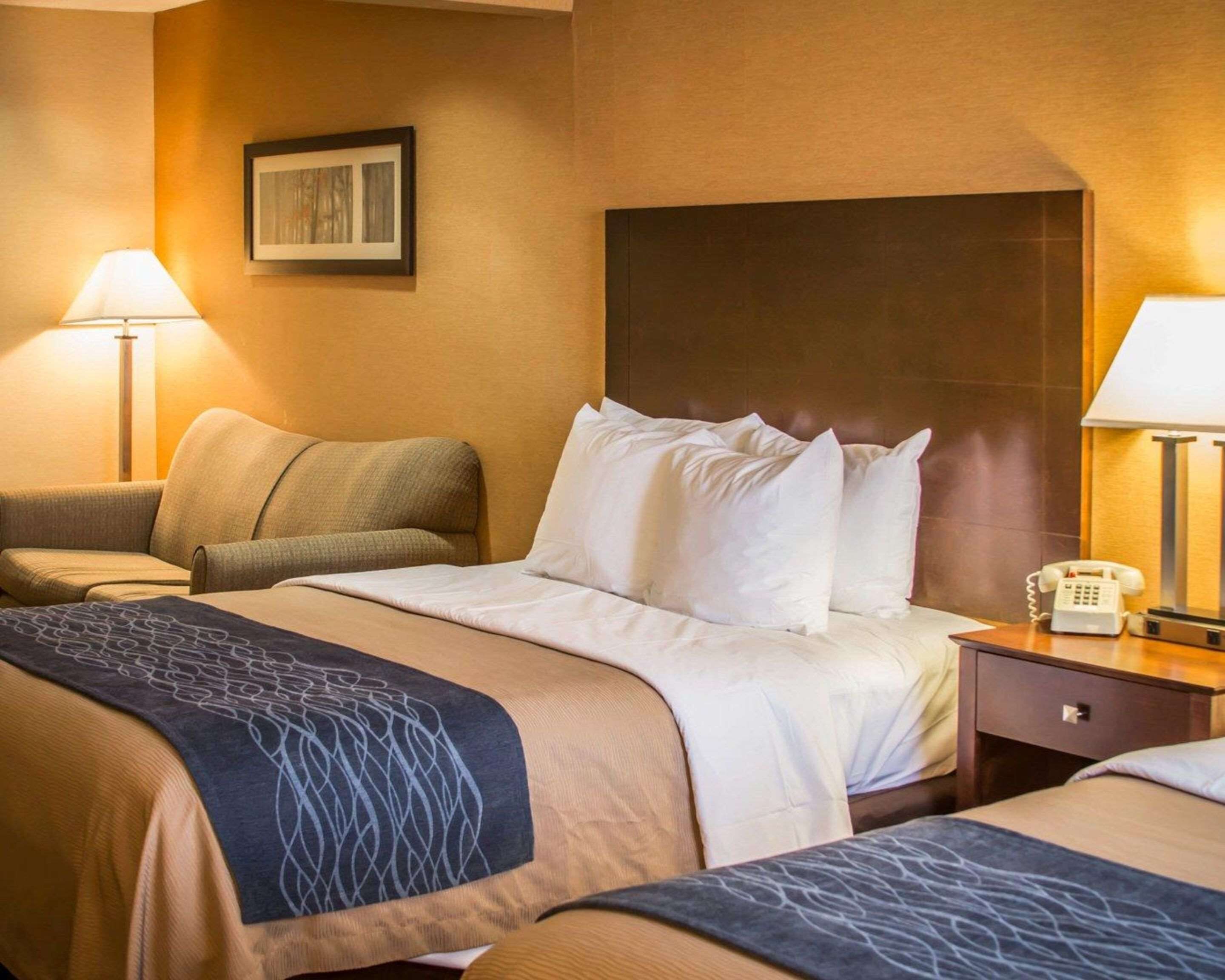 A hotel room with a large bed, two bedside tables, a chair, and a desk with a telephone.