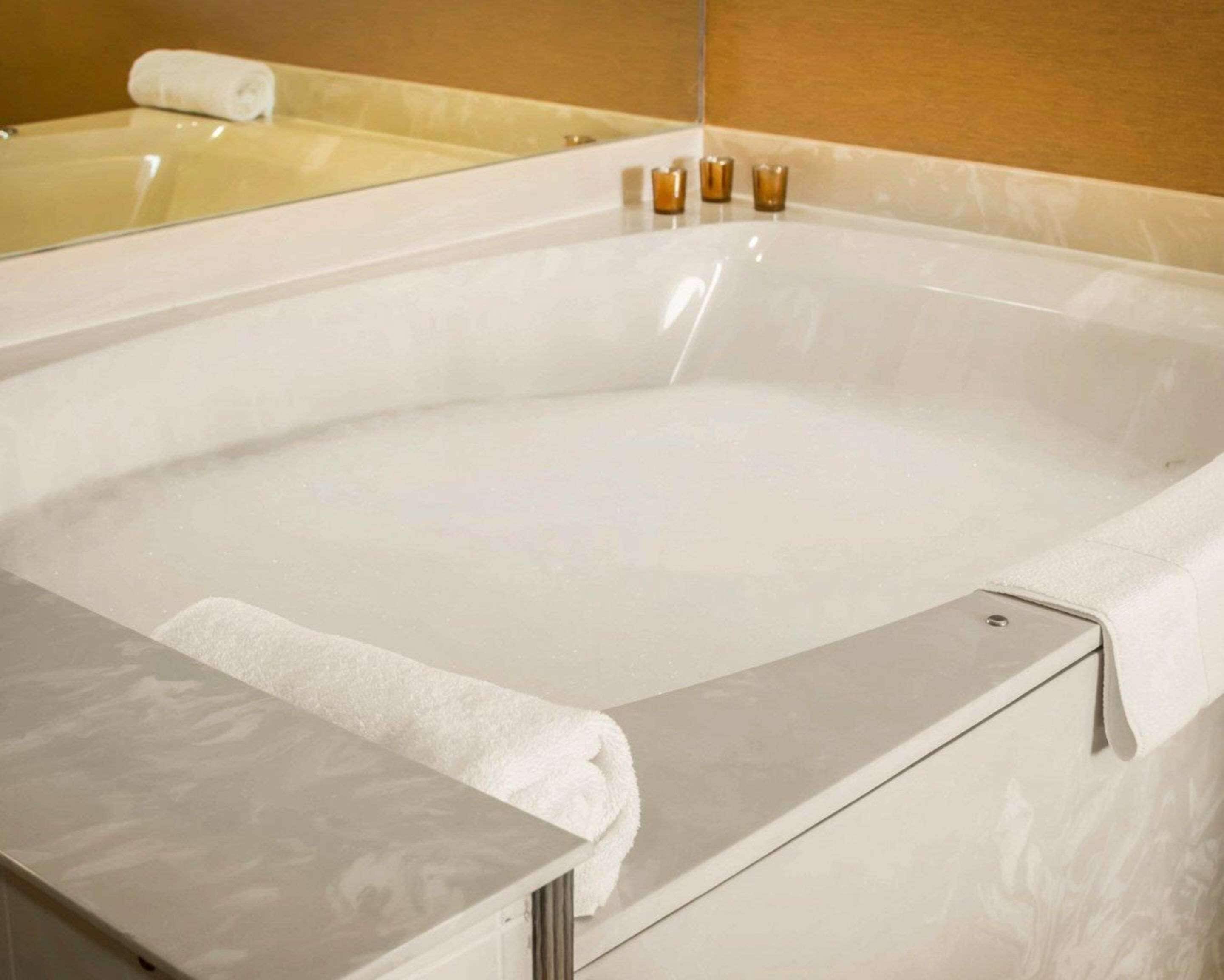 A large, empty bathtub with a white towel on the edge.
