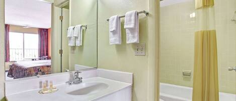 A bathroom with a white sink, a mirror, a shower curtain, and a bathtub.