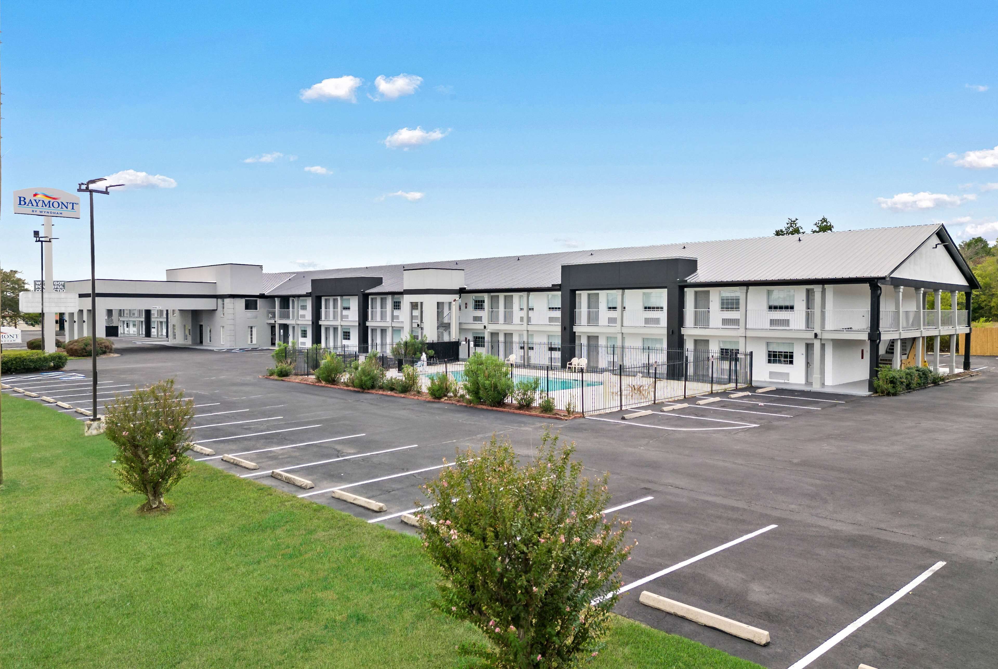 Un hôtel à plusieurs étages doté d’un parking, d’une piscine et d’une enseigne indiquant qu’il s’agit d’un hôtel Baymont.
