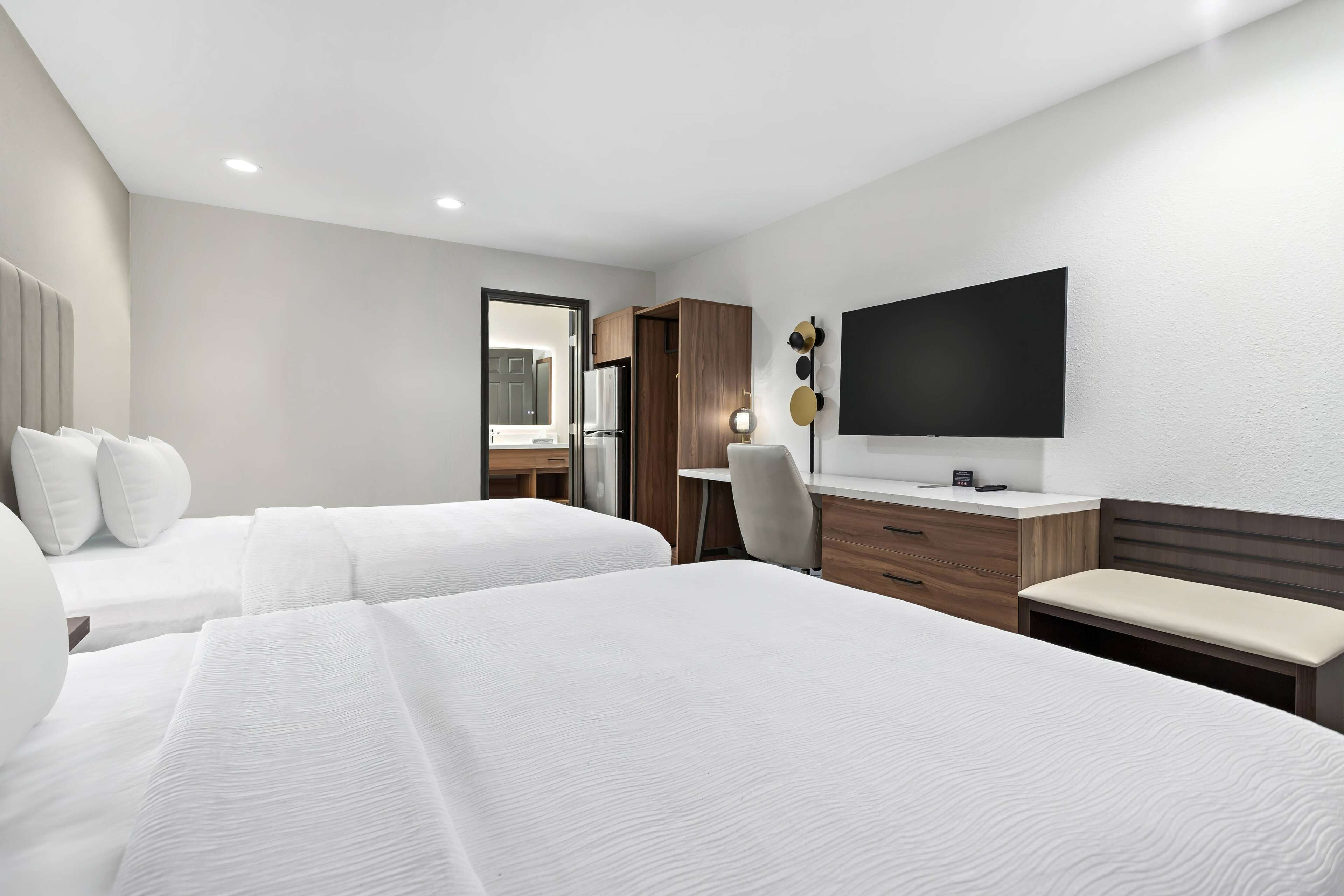 Une chambre d’hôtel avec deux lits, un bureau, une chaise, une télévision et une armoire.