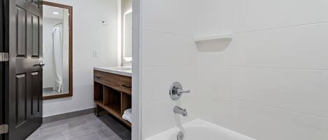 Ein modernes Badezimmer mit einer weißen Badewanne, einem Holzwaschtisch und einem großen Spiegel.