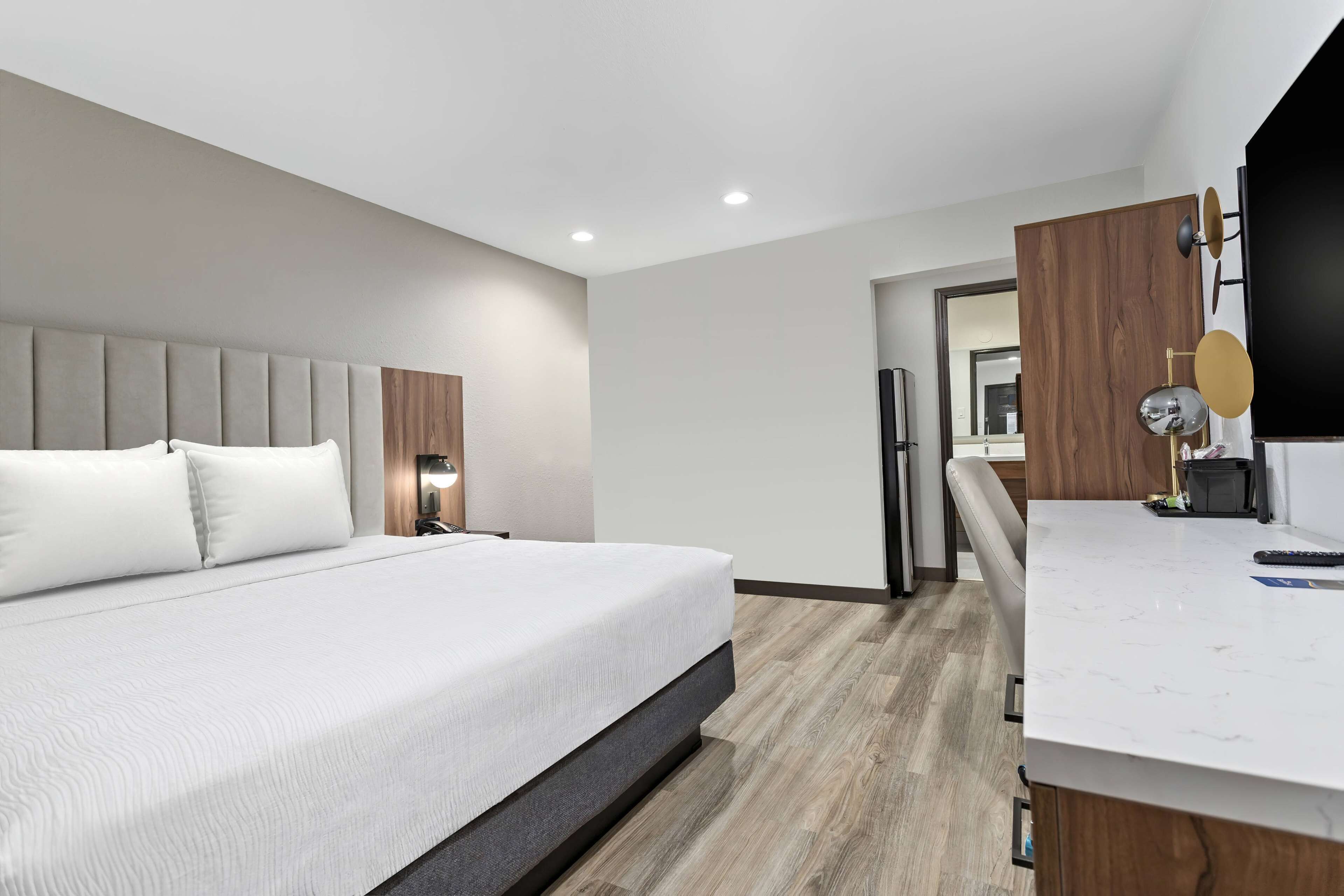A modern hotel room with a large bed, a desk, and a mirror.