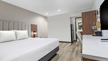 A modern hotel room with a large bed, a desk, and a mirror.