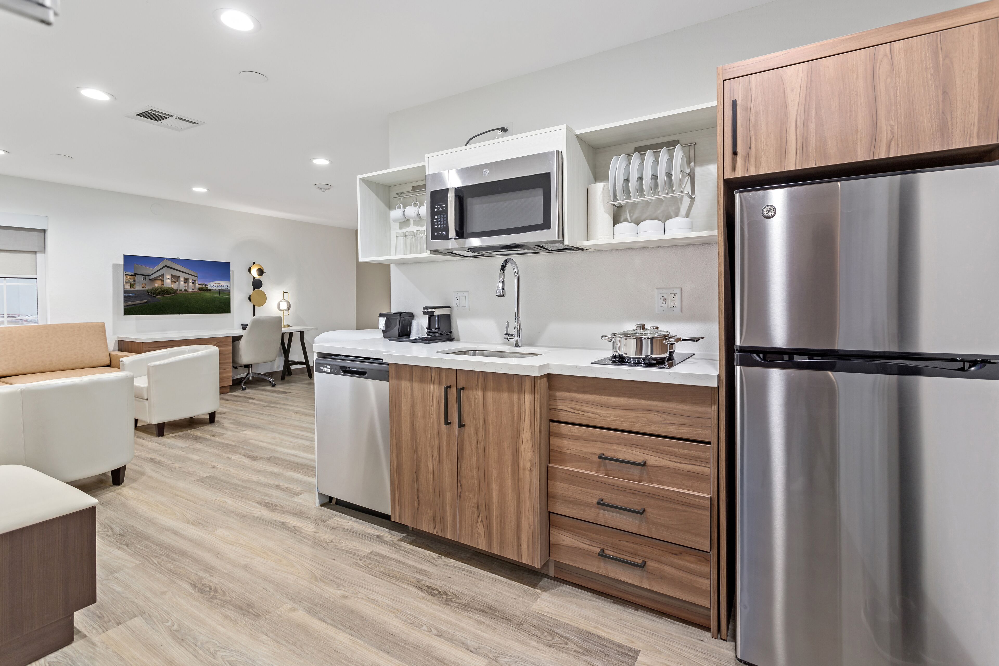 A modern kitchen with stainless steel appliances, wooden cabinets, and a white countertop.