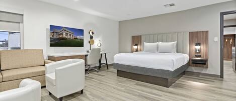 Quarto de hotel moderno com uma cama grande, uma escrivaninha, um sofá e uma cadeira.
