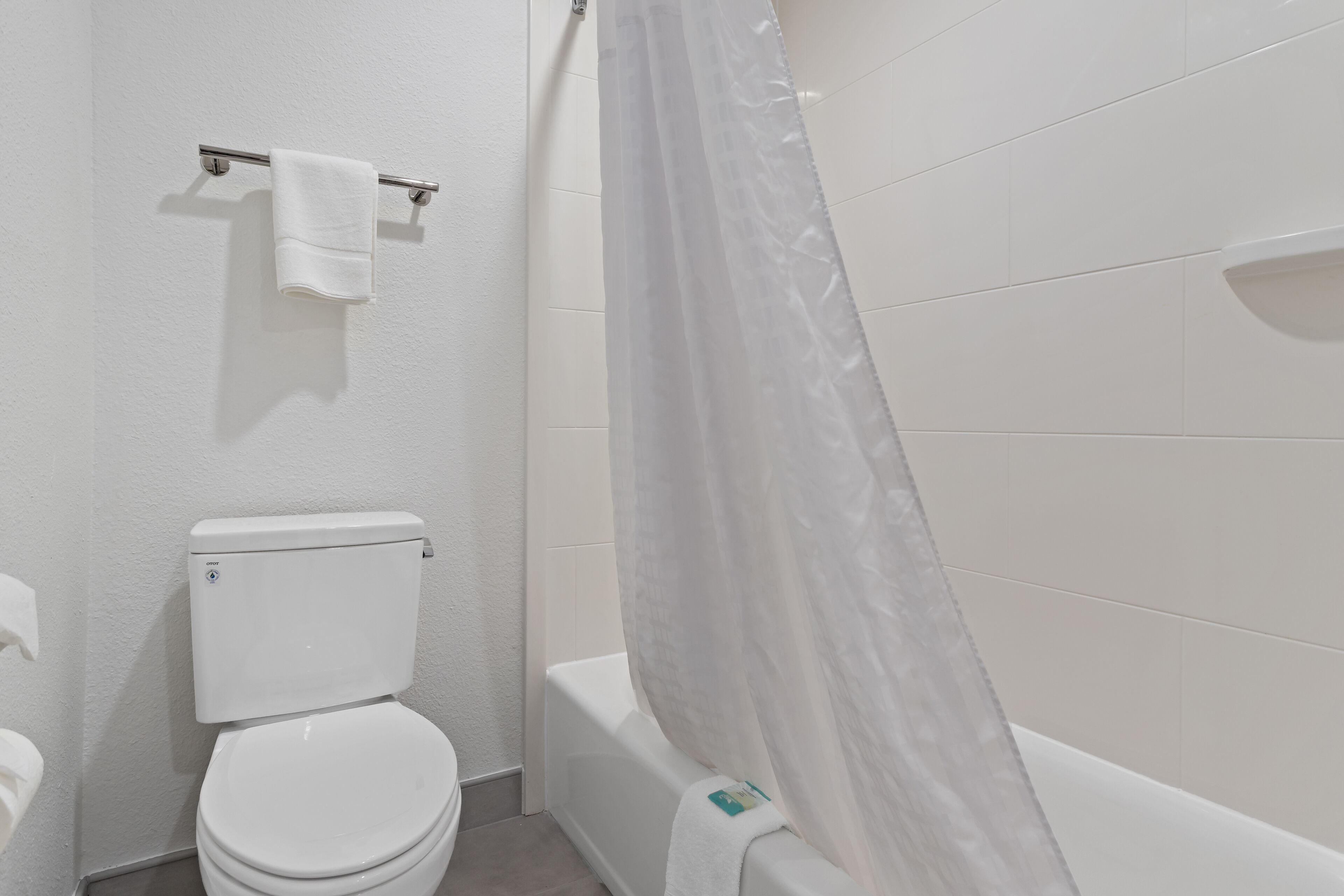 Un baño con inodoro, bañera y cortina de ducha.