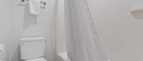 Une salle de bain équipée de toilettes, d’une baignoire et d’un rideau de douche.