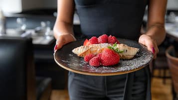 A person holding a plate with a dessert and strawberries.