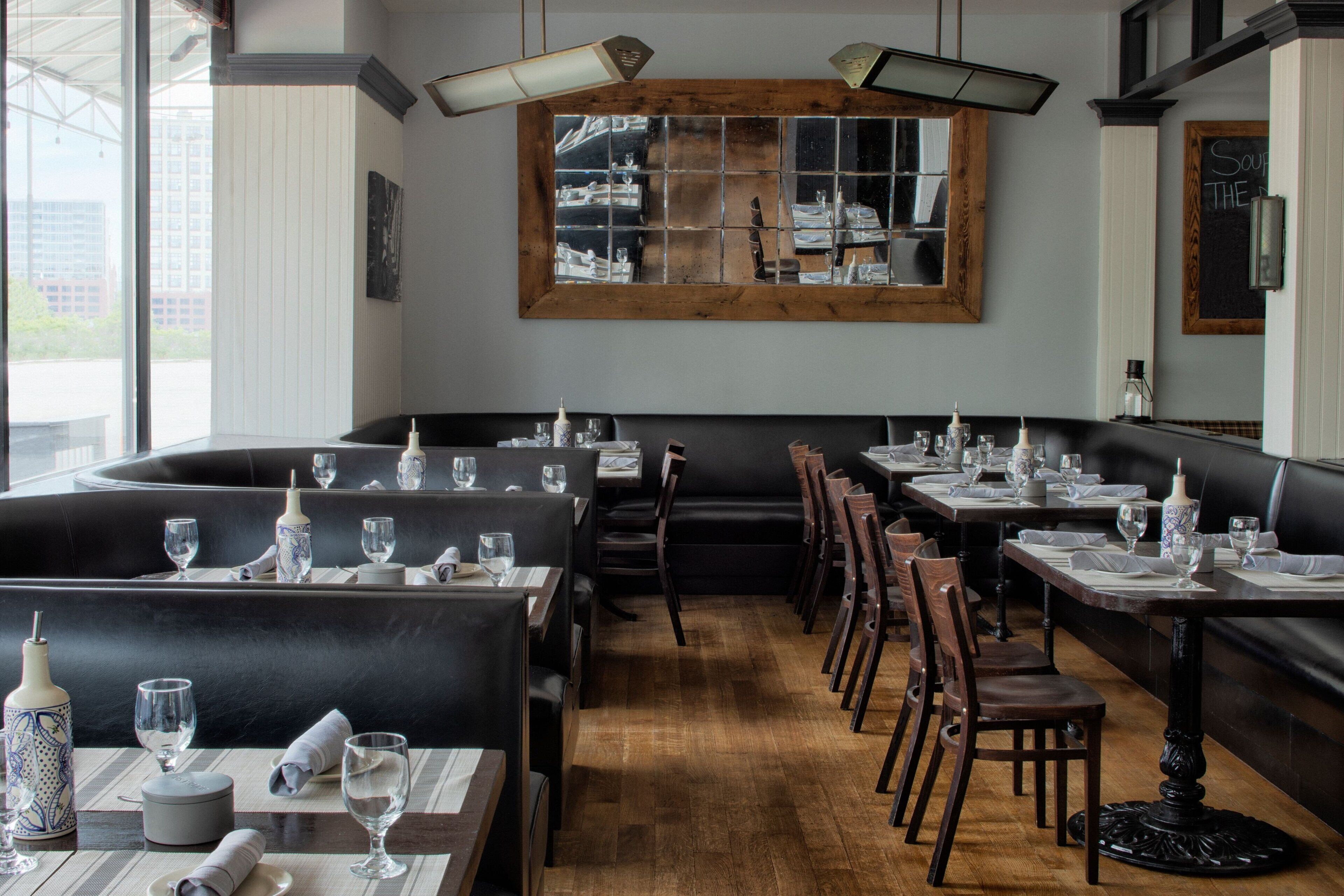 Ein Restaurant mit Sitzboxen und Tischen, Holzboden und einem großen Fenster mit Blick.