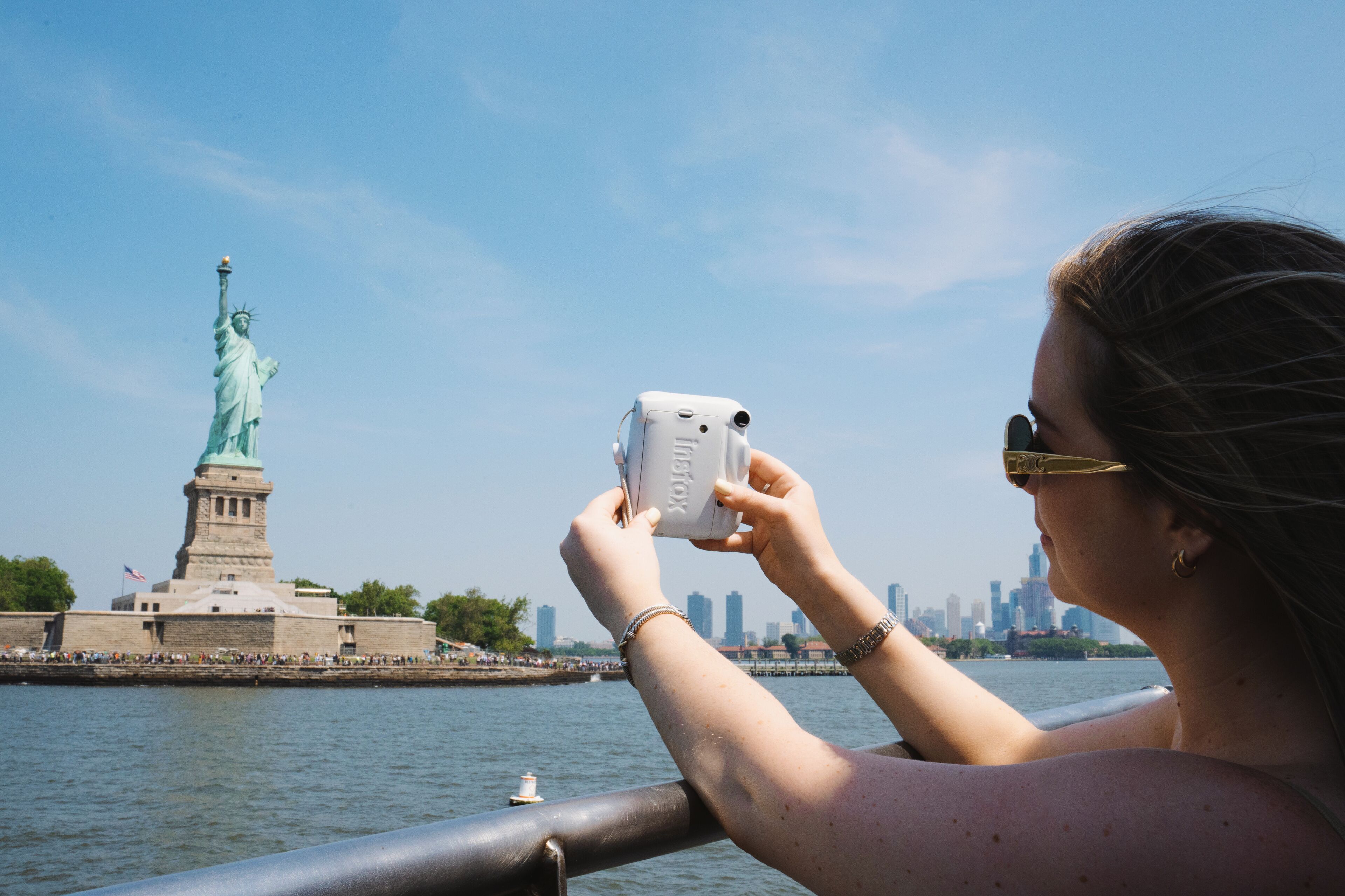 A person taking a photo with a camera near the Statue of Liberty.