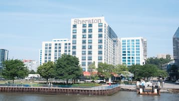 A Sheraton hotel with a modern design, located near a waterfront with a pedestrian bridge.