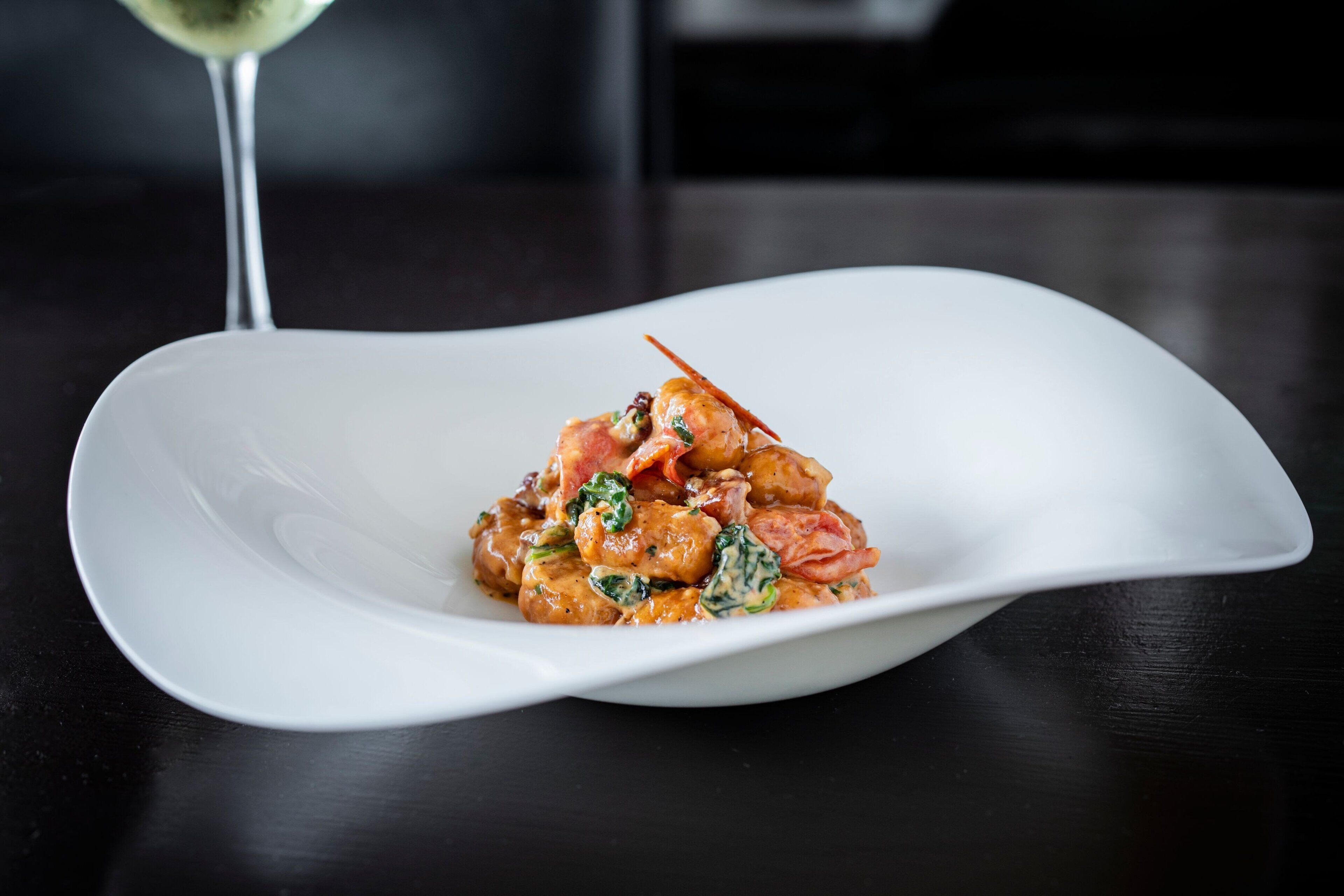 A white plate with a seafood dish on a dark table.