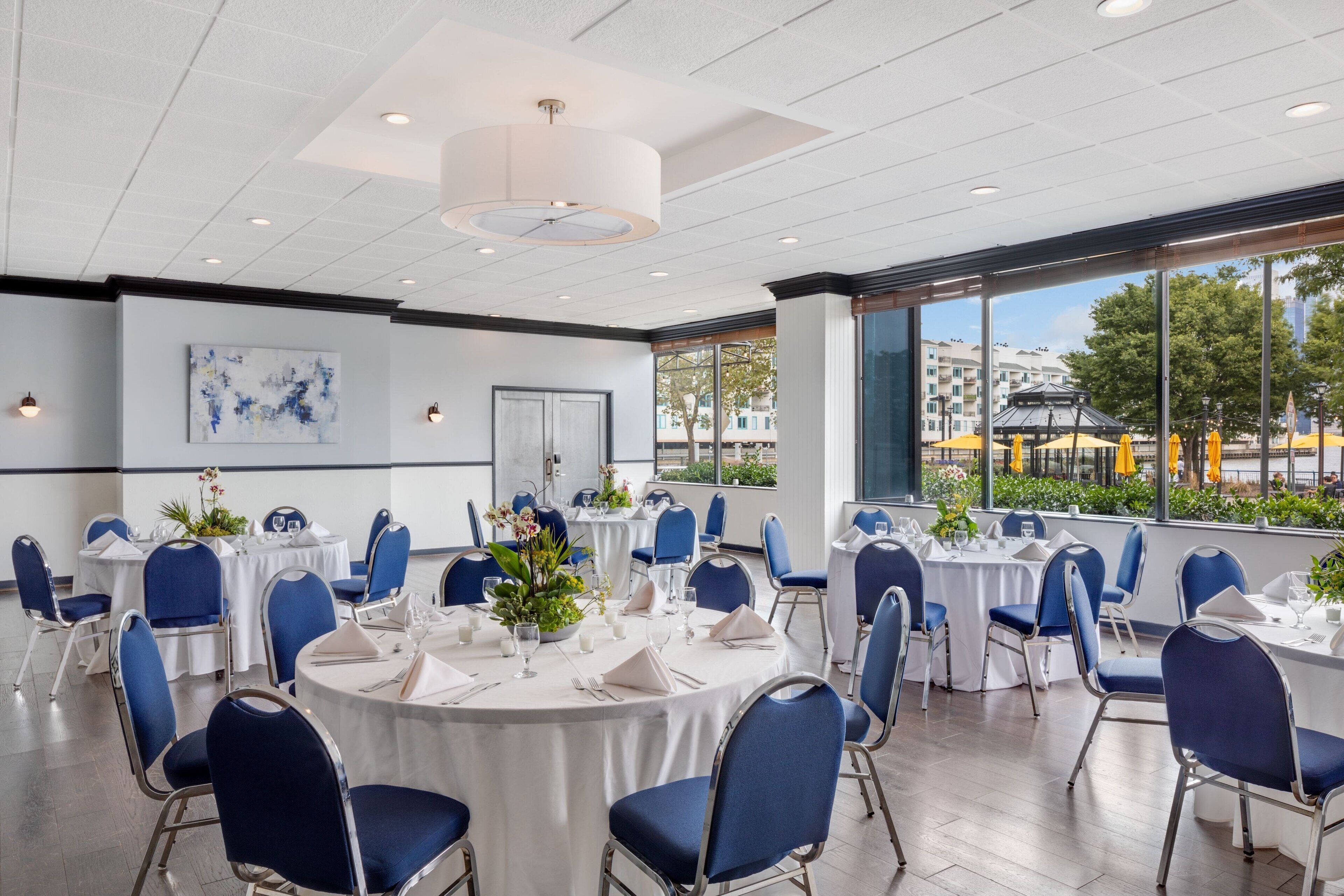 Une salle de conférence avec des tables rondes, des chaises bleues et des nappes blanches.