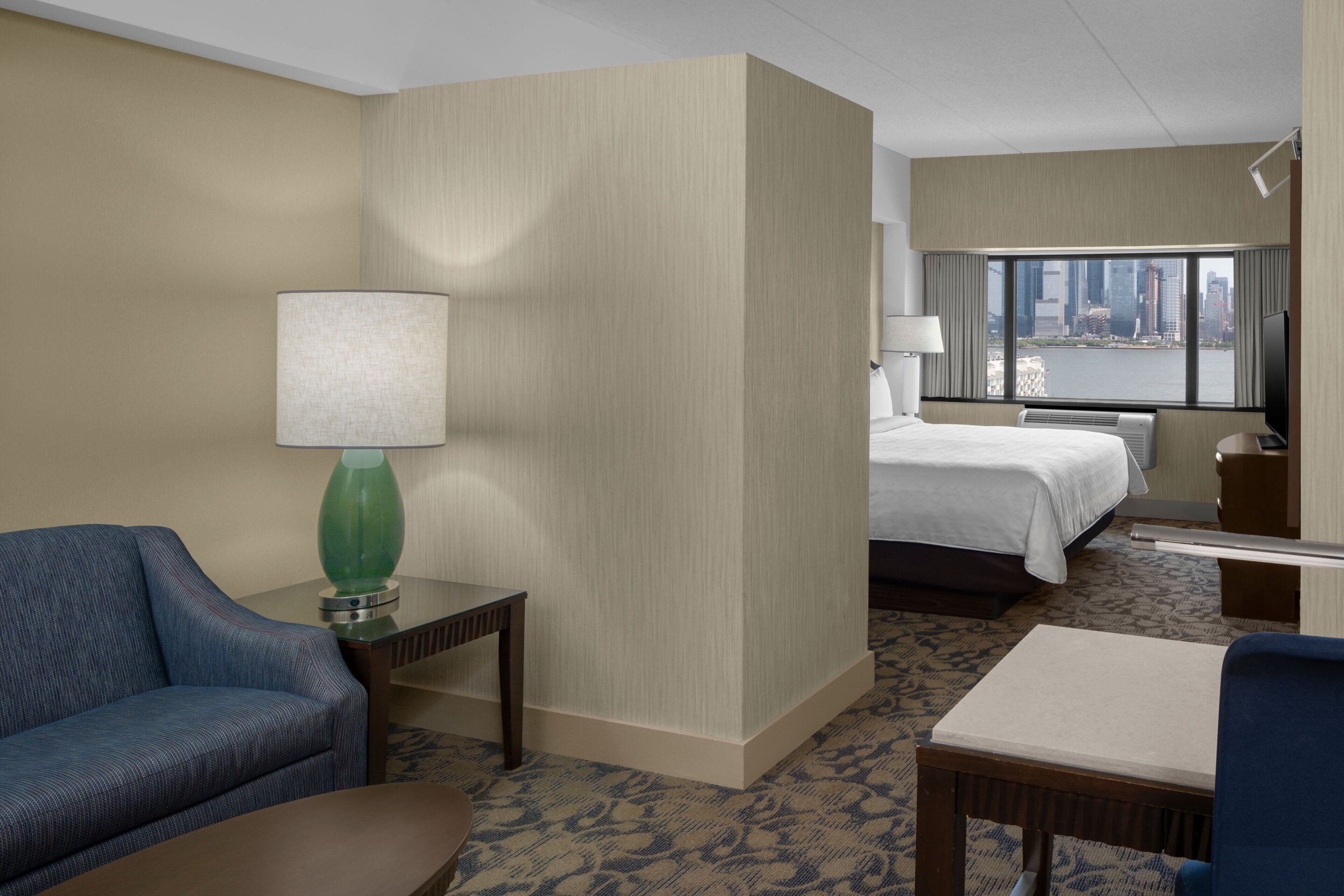 Een hotelkamer met een bed, een bureau, een stoel, een bank en een lamp.